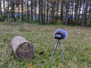 Photo of a digital recorder in a field with trees and mountains